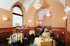 a dining room with tables and chairs and chandeliers at Hotel Patria in Rome