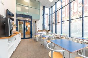 une cafétéria avec des tables, des chaises et des fenêtres dans l'établissement Zenitude Hôtel-Résidences Le Havre, au Havre