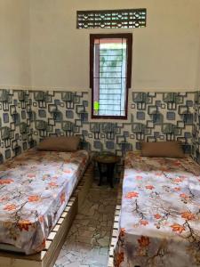 two beds sitting in a room with a window at Ohana Homestay Banyuwangi in Banyuwangi