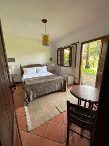 a bedroom with a bed and a table and a window at Vila ORIBA in Santo André