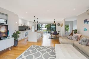 a large living room with a couch and a kitchen at Plan Beach in Merimbula