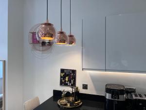 a kitchen with three pendant lights over a counter at Luxury Birmingham 2 Bedroom Town House in Birmingham +12 photos