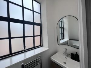 a bathroom with windows and a sink and a mirror at Luxury Birmingham 2 Bedroom Town House in Birmingham