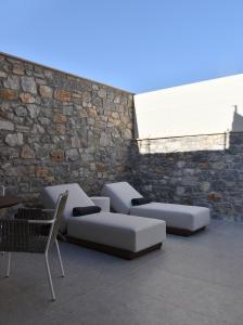 2 canapés blancs, une chaise et un mur en briques dans l'établissement Paligremnos Infinity, à Plakias