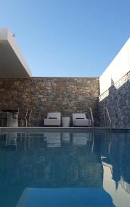 basen z 2 leżakami obok ściany z cegły w obiekcie Paligremnos Infinity w mieście Plakias