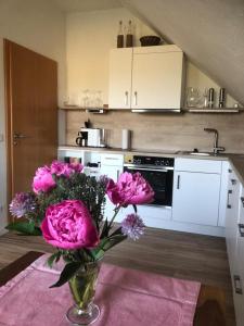 a vase with pink flowers on a table in a kitchen at Ferienwohnung auf dem Maifeld in Gappenach