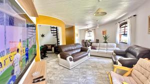 a living room with couches and a flat screen tv at Casa de Alto Padrão Itamambuca in Ubatuba