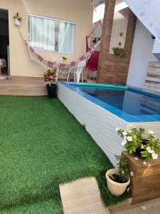 a backyard with a swimming pool and green grass at Casa Aconchegante com Piscina Barra do Jacuípe in Camaçari