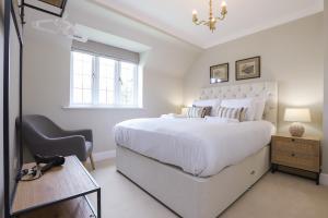 a white bedroom with a large white bed and a desk at The Stow Secret Cottage - Breathtaking 5BDR Cottage with Parking & Garden in Stow on the Wold