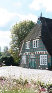 a red and green building with a black roof at Gut Moorbeck in Amelhausen