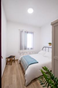 Un dormitorio blanco con una cama con una manta azul. en Casa Abuela Toña by Huskalia - city center, en Los Llanos de Aridane