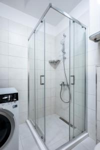 a shower with a glass door next to a washing machine at Urban Elegance at Its Finest Stylish 1-BD Flat in Sofia