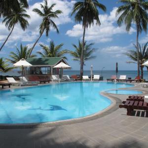 a pool with palm trees and the ocean in the background at Sea Lotus Park in Trincomalee