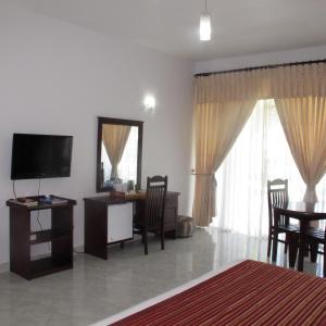 a living room with a television and a table and chairs at Sea Lotus Park in Trincomalee