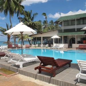 a swimming pool with lounge chairs and umbrellas at Sea Lotus Park in Trincomalee