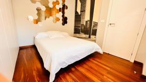 Habitación pequeña con cama blanca y suelo de madera. en VIGO CENTER SEREO OLD TOWN, en Vigo