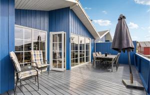 eine Terrasse mit einem Tisch, Stühlen und einem Sonnenschirm in der Unterkunft Pet Friendly Home In Hvide Sande With Sauna in Hvide Sande