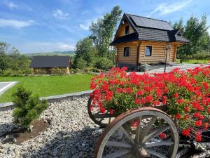 a wooden house with a cart with flowers in front of it at Domki Na Wypasie in Białka Tatrzańska