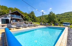 a swimming pool with chairs and a house at Stunning Home In Gospic With Outdoor Swimming Pool, Wifi And 2 Bedrooms in Gospić