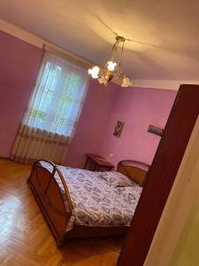 um quarto com uma cama e uma parede roxa em Mtatsminda Apartment Best View em Tbilisi