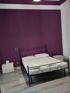 1 dormitorio con 1 cama con pared morada en casa Giuseppe, en Catania