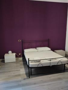 1 dormitorio con cama y pared púrpura en casa Giuseppe, en Catania