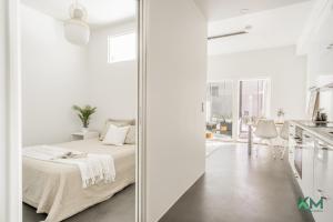 a white bedroom with a bed and a kitchen at Kotimaailma - Kaunis ja hyvin valoisa kaksio Vantaalta in Vantaa