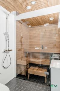 a shower in a bathroom with a wooden ceiling at Kotimaailma - Kaunis ja hyvin valoisa kaksio Vantaalta in Vantaa