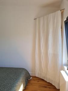 a bedroom with a bed and a curtain at Studio en plein centre-ville de Perros-Guirec in Perros-Guirec