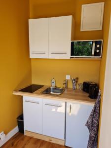 a small kitchen with white cabinets and a sink at Studio en plein centre-ville de Perros-Guirec in Perros-Guirec +10 photos