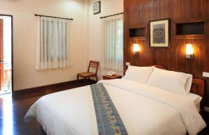 1 dormitorio con 1 cama blanca grande y 1 silla en Pakhongthong Villa, en Luang Prabang