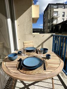 a wooden table with plates and bowls on a balcony at Convivial appartement de charme avec balcon , 95 m2 en hyper-centre de Saint-Brieuc. Tout confort, grand salon avec vidéoprojecteur - 3 chambres - Parking in Saint-Brieuc