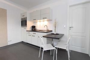 uma cozinha com armários brancos e uma mesa e cadeiras em Bungalow Mariannenweg 4 em Tarnewitz