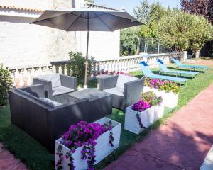 a patio with chairs and flowers and an umbrella at Villa Fuji Sierra de la Pandera Jaén in Jaén