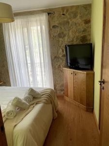 a bedroom with a bed and a television on a wooden cabinet at Casa Rochiña in Pobra do Caramiñal