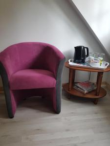 Vouzon的住宿－Le Clos des Écureuils，一张紫色椅子,坐在桌子旁,配有咖啡壶