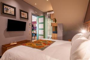 um quarto com uma cama branca e uma televisão de ecrã plano em Vila Origens Boutique Hotel Albufeira – Adults Only em Albufeira