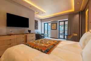 um quarto com uma cama grande e uma televisão de ecrã plano em Vila Origens Boutique Hotel Albufeira – Adults Only em Albufeira