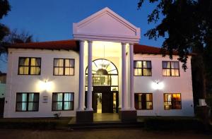a large white building with columns at night at The Emerald in Pretoria