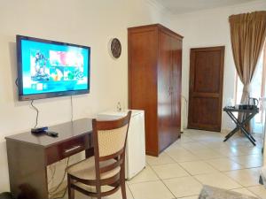 a living room with a desk and a television on the wall at The Emerald in Pretoria