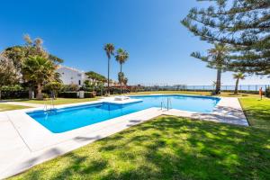 una piscina en un patio con palmeras en Calahonda Beach I Apartment with Sea View en Mijas Costa