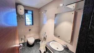a bathroom with a sink and a toilet and a mirror at Hotel Sumanchandra Suites in Nashik