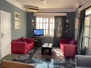 sala de estar con 2 sillas rojas y TV en PORTO HILL en Hurghada