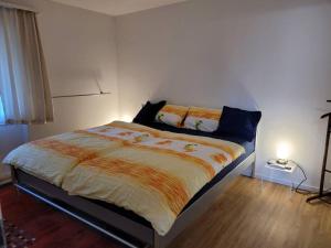 a bedroom with a bed with an orange and white comforter at Alpine Stay Thun Gateway to Interlaken & Bernese Oberland in Einigen