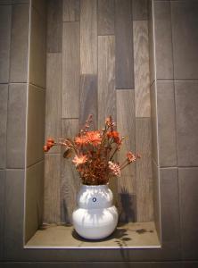 a white vase with orange flowers in it on a shelf at La Vita Veluwe in Wapenveld