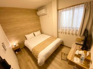 um quarto com uma cama, uma secretária e uma janela em AJITO Hostel & CafeBar em Shingu