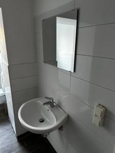 ein weißes Badezimmer mit einem Waschbecken und einem Spiegel in der Unterkunft zentrumsnahes Monteurszimmer in Erfurt