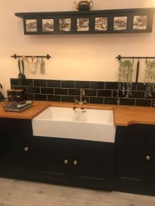 a white sink in a kitchen with black tiles at A luxury Boutique Barn set within 2 acre grounds 