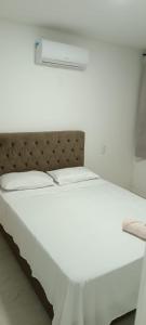 un letto bianco in una camera bianca con di Residencial clube praia dos anjos ad Arraial do Cabo
