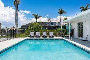 a swimming pool with chairs and a house at Good Vibes and Tan Lines! Private Beach with Heated Pool - Villa Good Times, Fort Myers Beach in Fort Myers Beach
